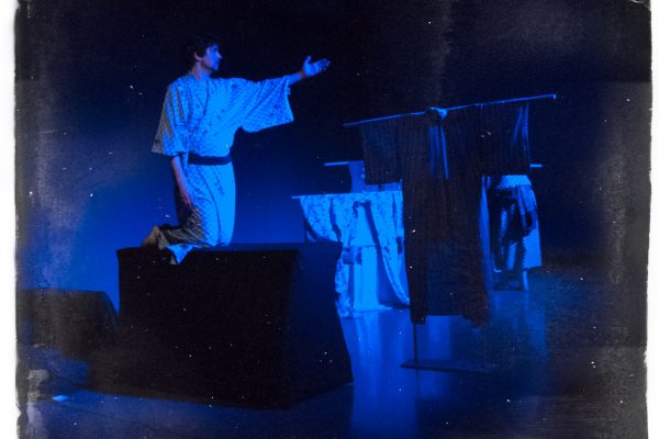 Naritsune (Andrew Woolner) rides the boat across the stage in Kikai-ga-shima.